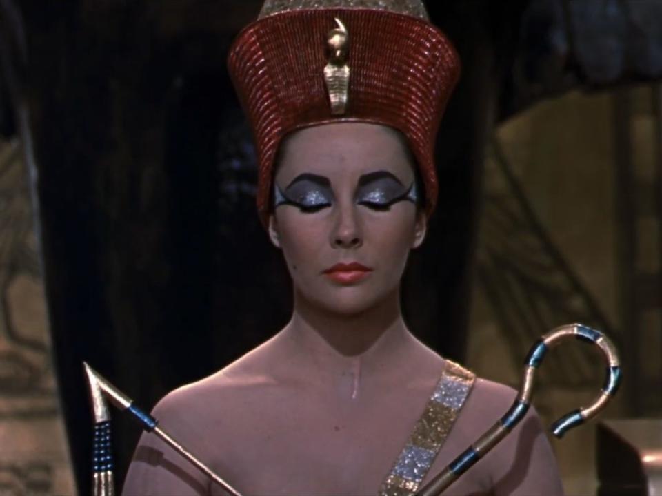 A picture of Elizabeth Taylor playing Cleopatra shows an elaborate headdress. Taylor is wearing heavy eye liner that flares out towards the temples.