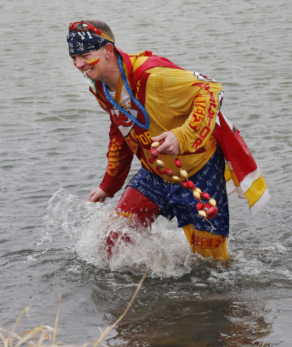 Kansas City Chiefs fan Ty Rowton, known as XFactor, retrieves part of his costume after takeing a Plunge for Landon in a farm pond near Bonner Springs, Kan., Friday, April 4, 2014. A 5-month-old boy's battle with cancer has inspired hundreds to jump into cold bodies of water, from a local golf course pond to the Gulf of Mexico and even the Potomac River in Washington, D.C. (AP Photo/Orlin Wagner)