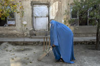 An Afghan woman poses for a photo with her cricket bat in Kabul, Afghanistan, Friday, Nov. 11, 2022. The ruling Taliban have banned women from sports as well as barring them from most schooling and many realms of work. A number of women posed for an AP photographer for portraits with the equipment of the sports they loved. Though they do not necessarily wear the burqa in regular life, they chose to hide their identities with their burqas because they fear Taliban reprisals and because some of them continue to practice their sports in secret. (AP Photo/Ebrahim Noroozi)