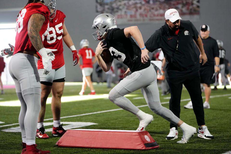 Mar 5, 2024; Columbus, OH, USA; Ohio State Buckeyes quarterback Devin Brown (33) runs past head coach Ryan Day during the first spring practice at the Woody Hayes Athletic Center.