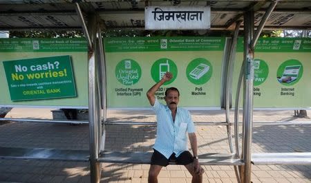 A man exercises on a bus stop with hoardings promoting digital payments in Mumbai, India, January 27, 2017. Picture taken January 27, 2017. REUTERS/Shailesh Andrade/File Photo