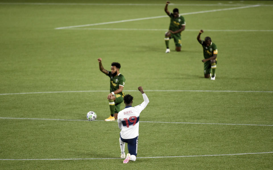 Vancouver Whitecaps midfielder Janio Bikel, center, kneels before the MLS soccer match against the Portland Timbers in Portland, Ore., Sunday, Sept. 27, 2020. (AP Photo/Steve Dykes)