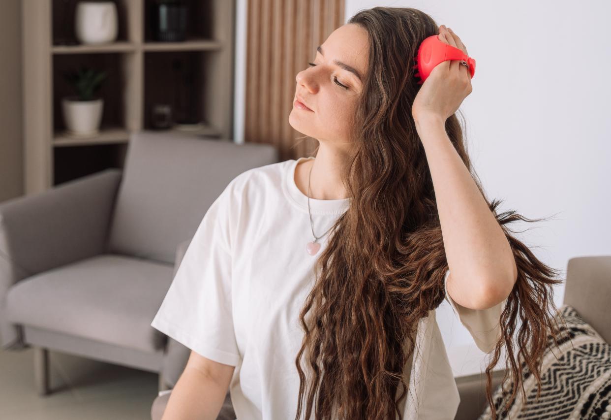 Lady takes care of scalp by doing massage with scalp massager.