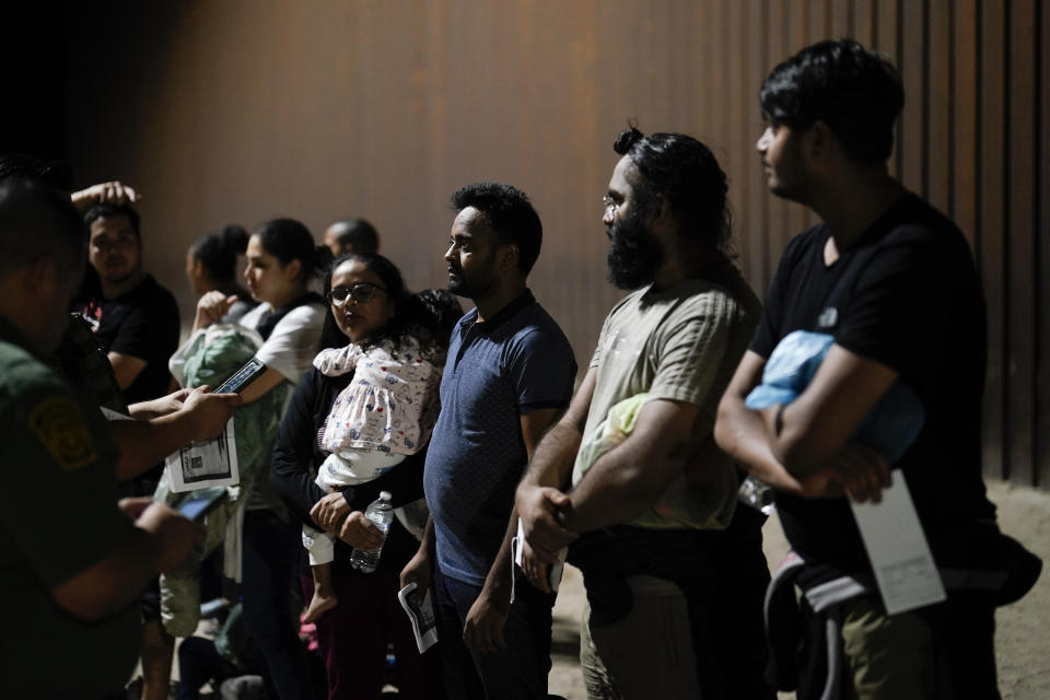 People wait in line after crossing the border from Mexico and surrendering to U.S. authorities to apply for asylum near Yuma, Arizona, Tuesday, Aug. 23, 2022. (AP Photo/Gregory Bull)