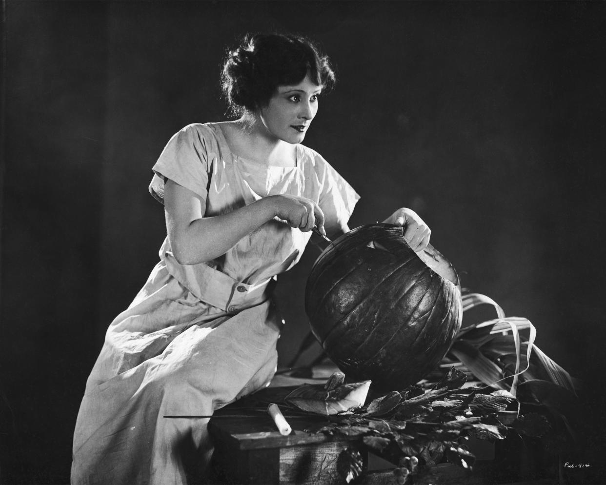 American actress Eleanor Boardman carving a pumpkin into a lantern for Halloween, circa 1925.