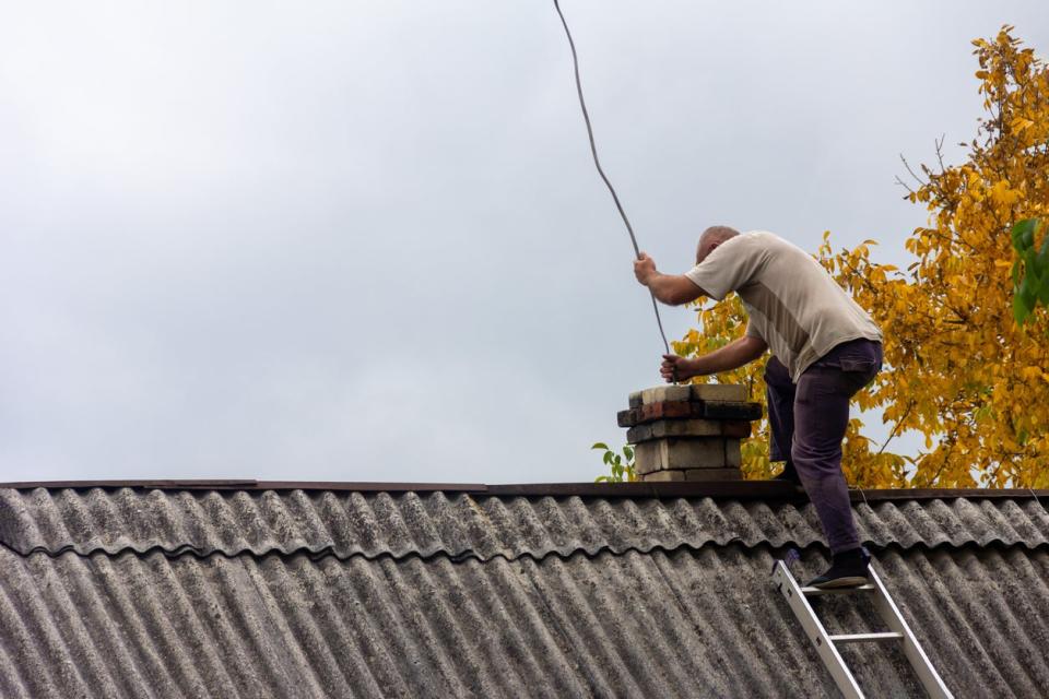 A chimney sweep on the roof of a house.