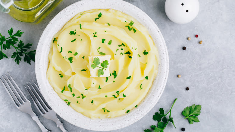 potato puree with parsley in white bowl on grey countertop 
