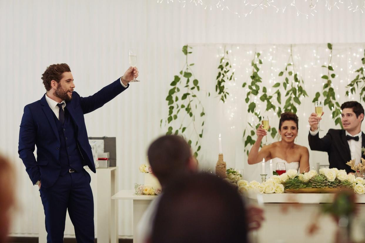 Shot of a young man giving a toast and speech at a wedding reception