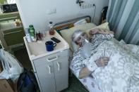 An elderly woman suffering from COVID-19 breathes with the help of an oxygen mask in central district hospital of Kolomyia, western Ukraine, Tuesday, Feb. 23, 2021. After several delays, Ukraine finally received 500,000 doses of the AstraZeneca vaccine marketed under the name CoviShield, the first shipment of Covid-19 vaccine doses. The country of 40 million is one of the last in the region to begin inoculating its population. (AP Photo/Evgeniy Maloletka)