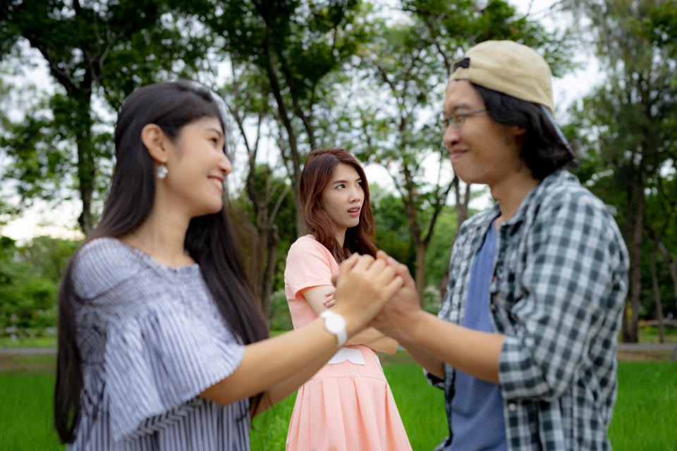 A woman greets a man with his girlfriend in the background in an awkward meeting.