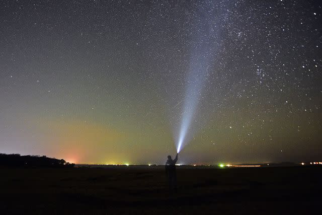 Yuri SmityukTASS via Getty Images A person points a light at the Orionid meteor shower