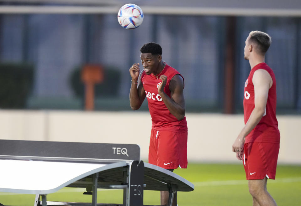 Canada forward Jonathan David, left, heads the ball while playing soccer with teammates using a table tennis surface during practice at the World Cup soccer tournament in Doha, Qatar on Tuesday, Nov. 29, 2022. (Nathan Denette/The Canadian Press via AP)