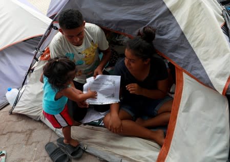Honduran migrants Marvin Madrid and his new wife Dexy Maldonado sit besides their daughter as they show their "Marriage Certificate" during an interview with Reuters in an encampment in Matamoros