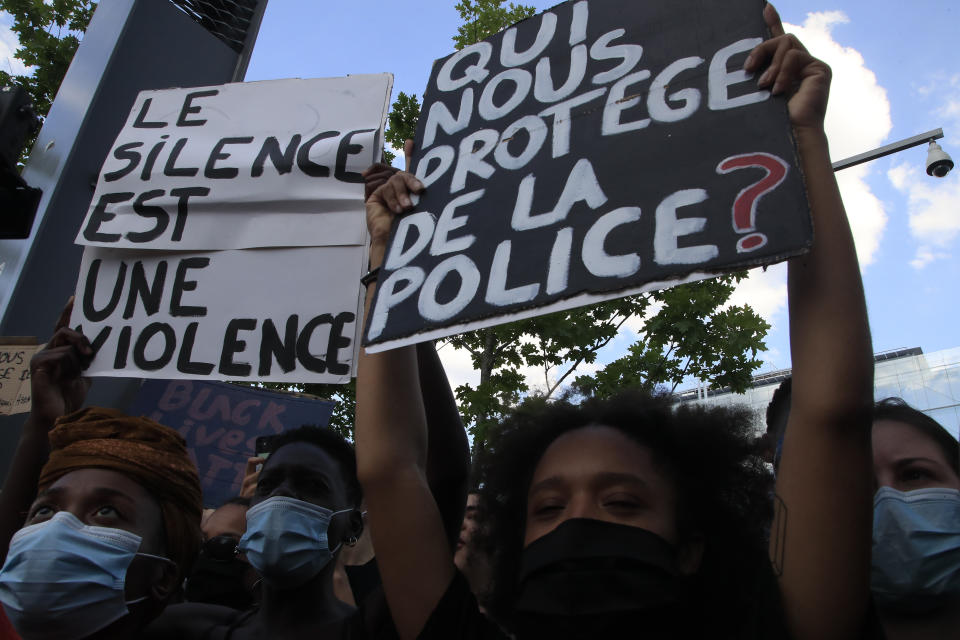 People protest with posters reading "Silence is violence" and "Who protects us from police" outside the Palace of Justice Tuesday, June 2, 2020 in Paris. French authorities banned the protest over racial injustice and heavy-handed police tactics as global outrage over what happened to George Floyd in the United States kindled frustrations across borders and continents. Family and friends of Adama Traore, a French black man who died shortly after he was arrested by police in 2016, call for a protest which will also pay homage to George Floyd. (AP Photo/Michel Euler)