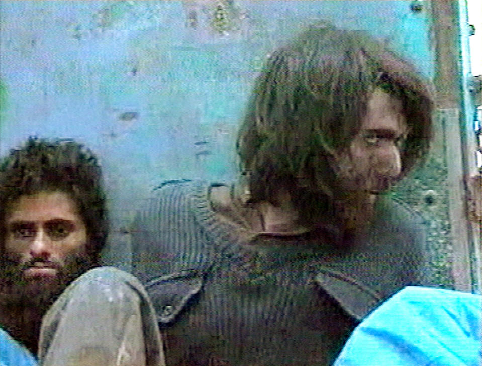 FILE - This file image taken Dec. 1, 2001, from television footage in Mazar-i-Sharif, Afghanistan, shows John Walker Lindh, right, claiming to be an American Taliban volunteer. Lindh, the young Californian who became known as the American Taliban after he was captured by U.S. forces in the invasion of Afghanistan in late 2001, is set to go free Thursday, May 23, 2019, after nearly two decades in prison. (AP Video, File)