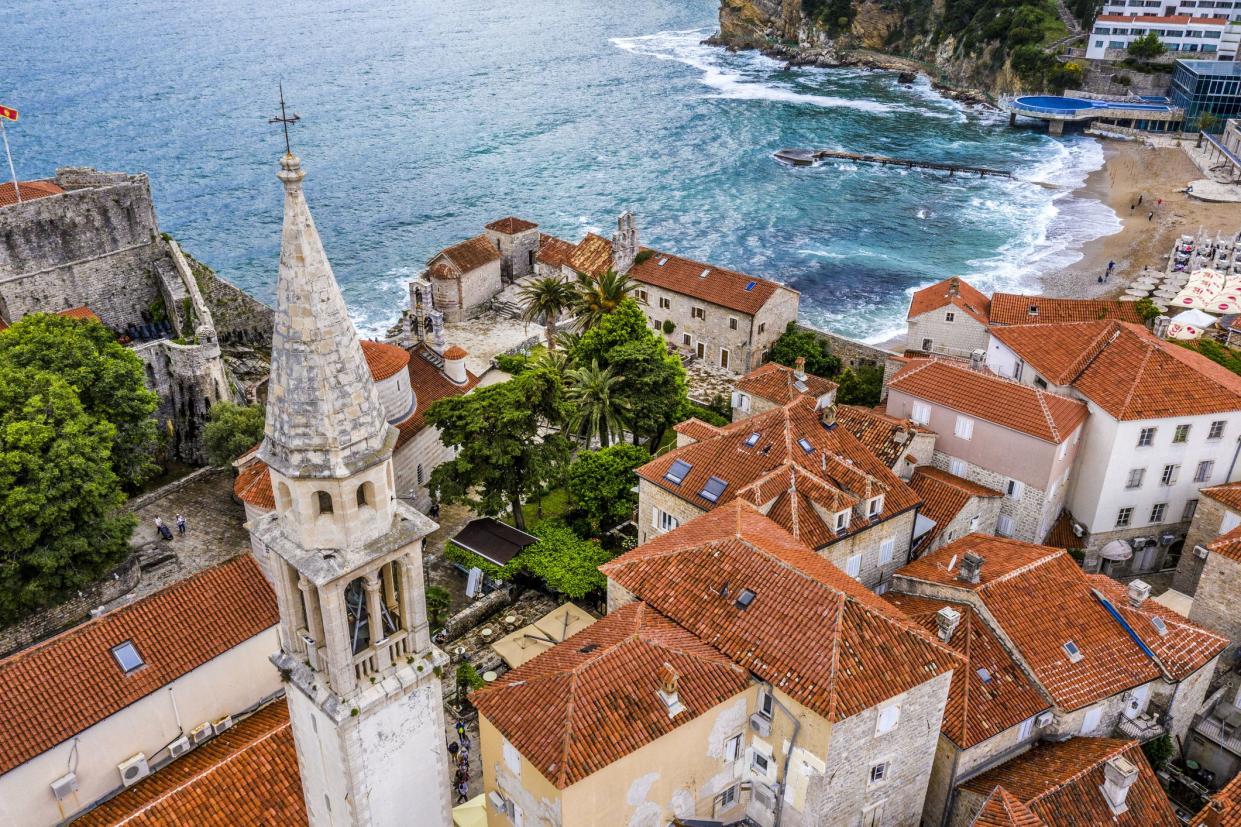 Church bell tower dominating over the rooftop of Old Town of Budva, taken from air.