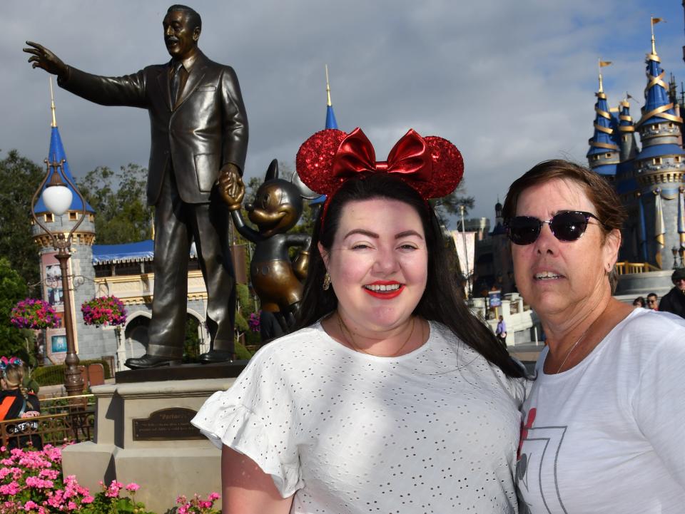megan and her mom posing in front of the partners statue at disney world