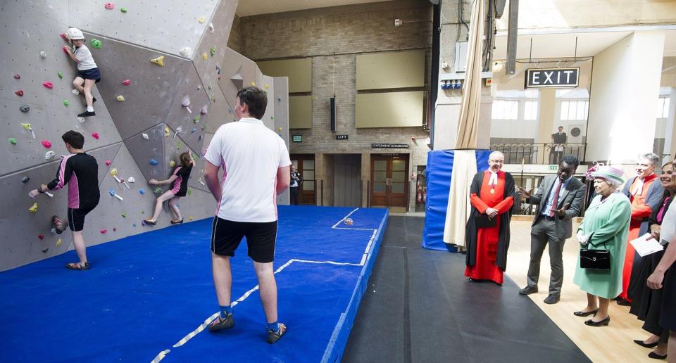 Britain's Queen Elizabeth II watches school pupils on a climbing wall during an engagment where she officially opened Westminster School's new Sports Centre in London on June 12, 2014.  