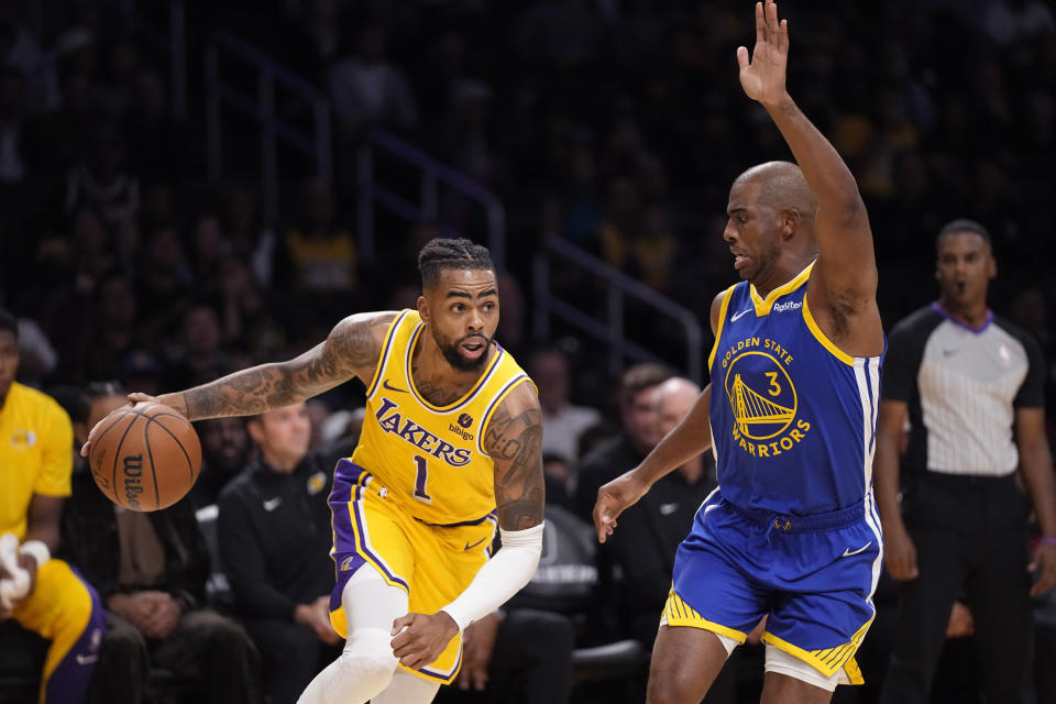 Los Angeles Lakers guard D'Angelo Russell, left, drives past Golden State Warriors guard Chris Paul during the first half of an NBA preseason basketball game Friday, Oct. 13, 2023, in Los Angeles. (AP Photo/Mark J. Terrill)