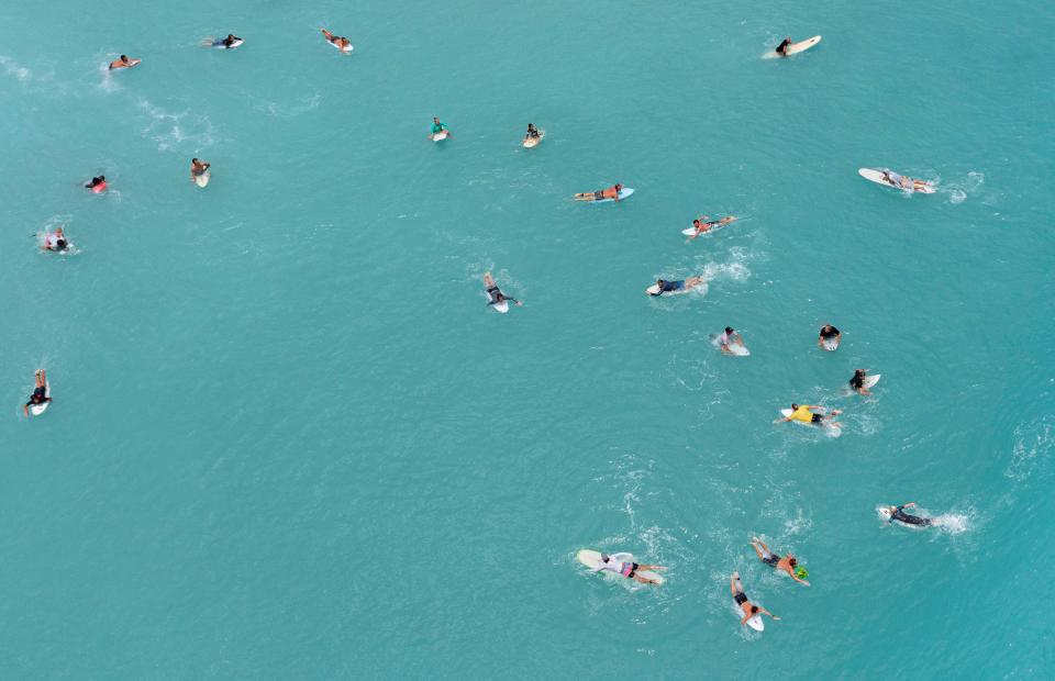 Surfers wait to catch a wave in Juno Beach, Florida on June 8, 2022. 