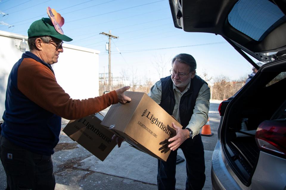 U.S. Senator Gary Peters, center, and volunteer Dennis Blender to load food items into a volunteer's vehicles for delivery to clients at the Lighthouse Emergency Services warehouse in Pontiac on Tuesday, Nov. 22, 2022. Blender also serves as a board member for Lighthouse MI.
