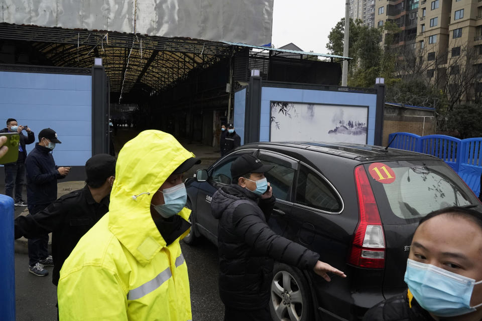 FILE - In this file photo dated Sunday, Jan. 31, 2021, security personnel clear the way for a convoy of the World Health Organization team to enter the Huanan Seafood Market on the third day of field visit in Wuhan in central China's Hubei province. International scientists have examined previously unavailable genetic data from samples collected at a market in China close to where the first human cases of COVID-19 were detected and said they have found suggestions the pandemic originated from animals, not a lab. (AP Photo/Ng Han Guan, File)