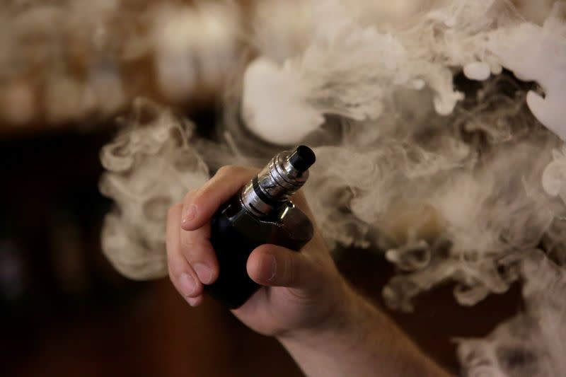 A man holds an electronic cigarette as he vapes at a Vape Shop in Monterrey