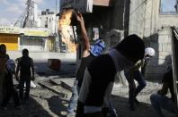 A masked Palestinian youth throws a petrol bomb towards Israeli security forces during clashes at the Qalandia checkpoint between Jerusalem and Ramallah, in the Israeli-occupied West Bank, on October 6, 2015