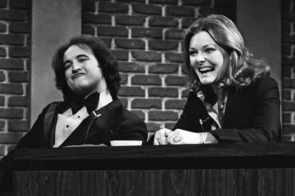 SATURDAY NIGHT LIVE -- Episode 11 -- Air Date 01/24/1976 -- Pictured: (l-r) John Belushi as Sheila Ellington, male impersonator, Jane Curtin during "Backstage Banter" sketch on January 24, 1976