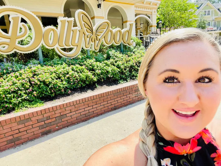carly posing for a selfie in front of the dollywood entrance sign