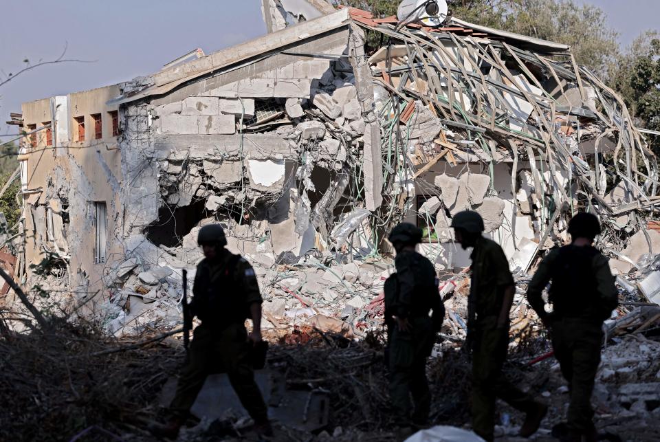 Israeli soldiers walk past a house destroyed in the October 7 attack by Palestinian Hamas militants on kibbutz Beeri near the border with Gaza, on October 14, 2023. Thousands of people, both Israeli and Palestinians have died since October 7, 2023, after Palestinian Hamas militants entered Israel in a surprise attack leading Israel to declare war on Hamas in the Gaza Strip enclave on October 8. (Photo by Thomas COEX / AFP) (Photo by THOMAS COEX/AFP via Getty Images)