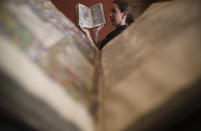 <p>A gallery assistant poses with a copy of the Book of Hours (c 1470’s) during a photo call for the Valuable Printed Books and Manuscripts auction at Christies in London, Britain May 20, 2016. (Neil Hall/REUTERS) </p>