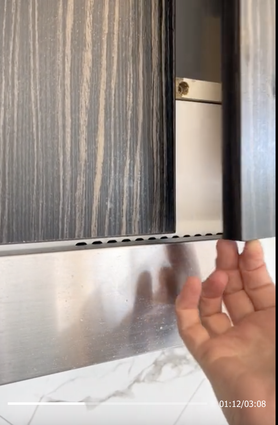 Hand opens a cupboard with a built-in organizer, in a kitchen setting