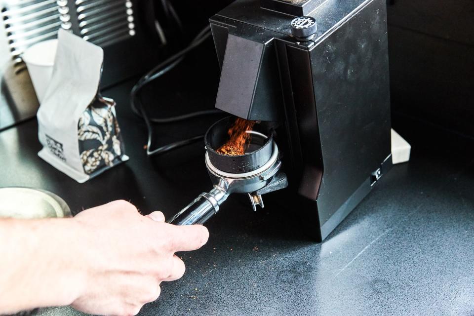 grinder emptying ground coffee beans into espresso tamper