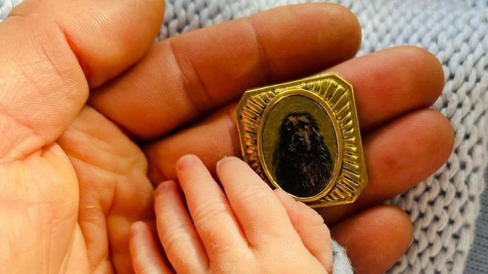 A baby hand with a pendant featuring a dog