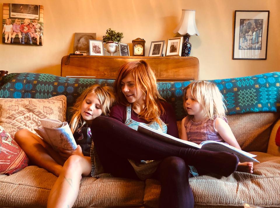 Mum sitting reading with her two daughters