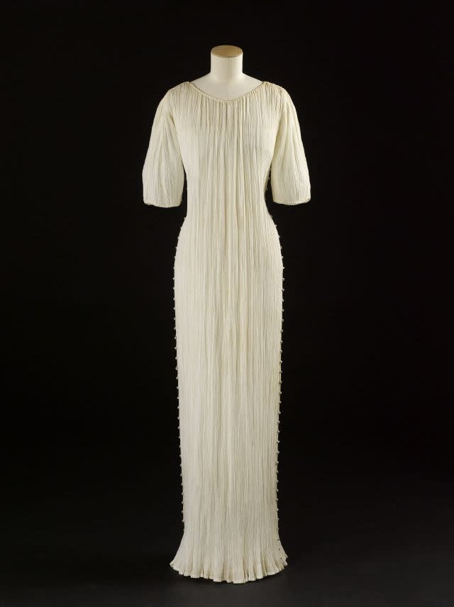 Mariano Fortuny (1871-1949). Delphos dress. Circa 1940s. Pleated white mercerized cotton canvas, white silk cordon. White, yellow and blue glass beads