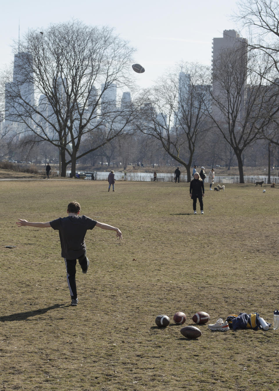 In this photo provided by Madeleine Beck, Declan Scheiner, 14, practices punting footballs to his mother, Bethany Scheiner, in Chicago’s Lincoln Park, Sunday, Feb. 25, 2024. They were among throngs of people who headed outside as temperatures reached into the 60s in Chicago and other Midwest areas. (Madeleine Beck via AP)
