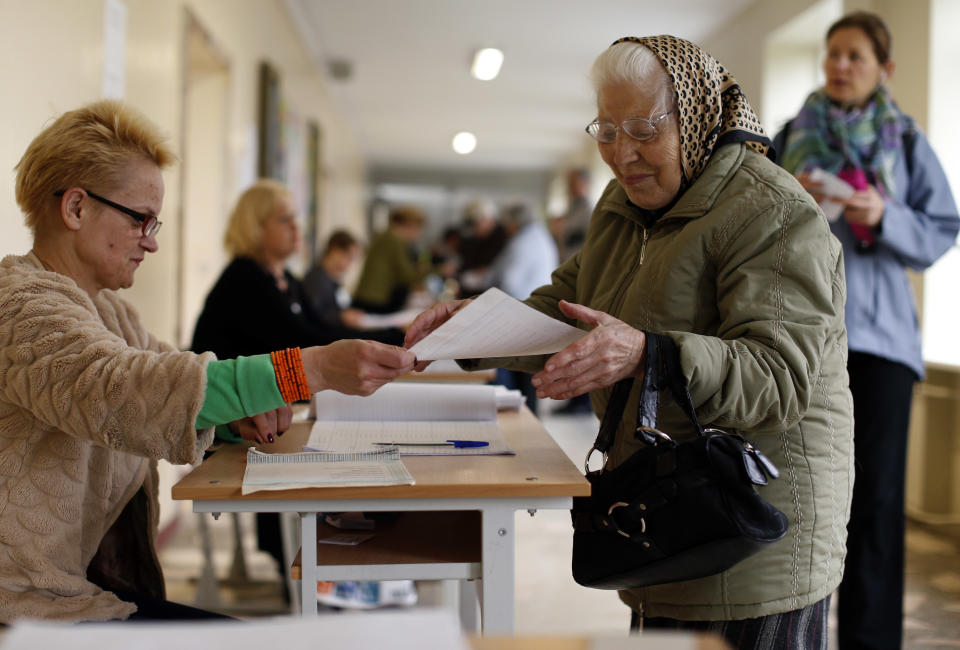 A Lithuanian woman takes a ballot papers at a polling station during the first round of voting in presidential elections in Vilnius, Lithuania, Sunday, May 11, 2014. Polls opened Sunday for the presidential election in Lithuania, where tough-talking incumbent Dalia Grybauskaite is widely expected to be re-elected for a second term. (AP Photo/Mindaugas Kulbis)