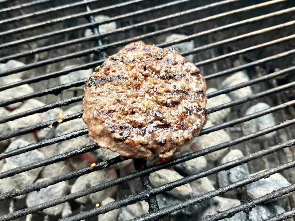 cooked burger patty on a charcoal grill