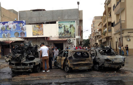 People look at the remnants of a car at the scene of a car bomb in Benghazi, Libya, November 21, 2016. REUTERS/Stringer