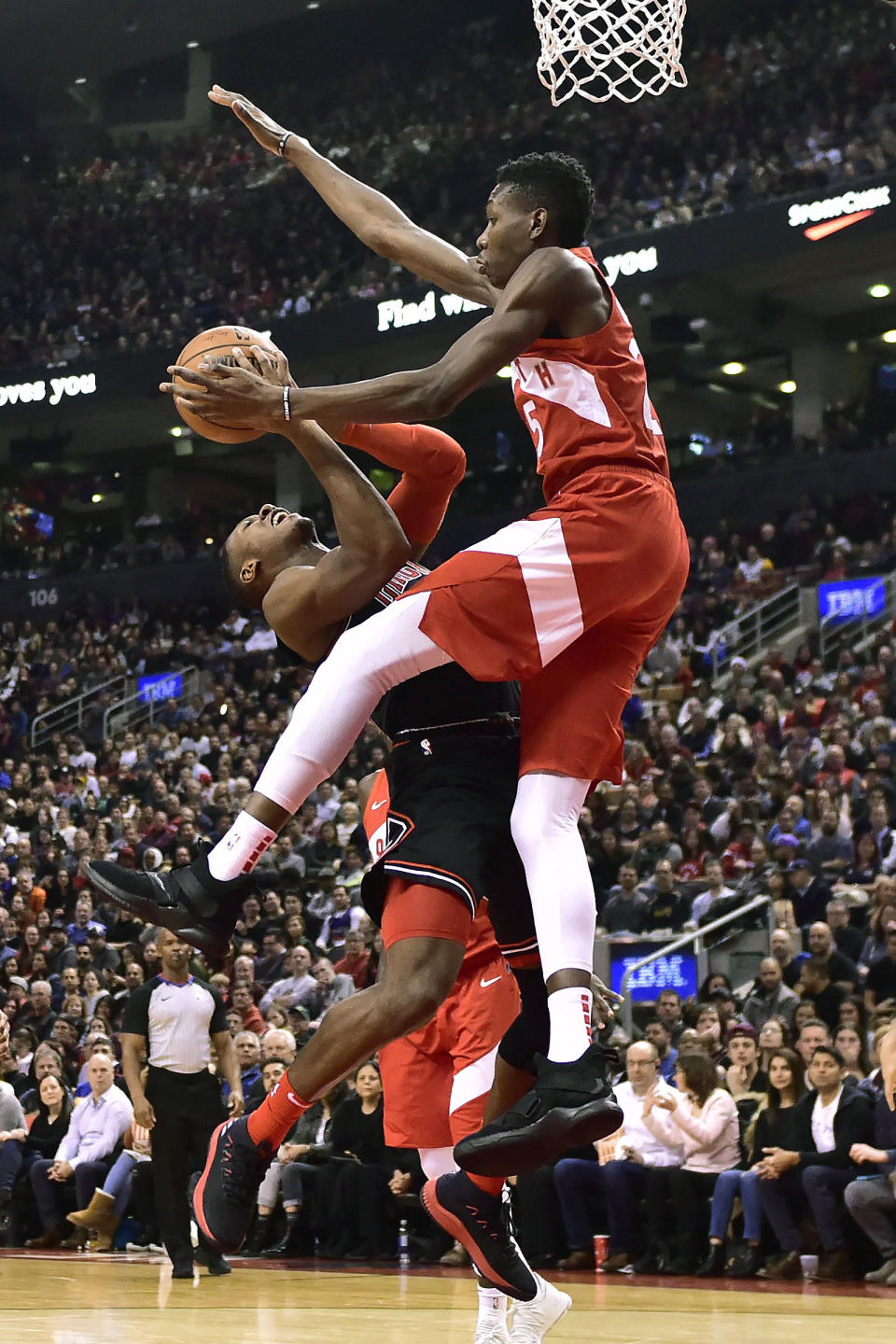 Toronto Raptors forward Chris Boucher (25) fouls Chicago Bulls guard Kris Dunn (32) driving to the net during the first half of an NBA basketball game, Sunday, Dec. 30, 2018 in Toronto. (Frank Gunn/The Canadian Press via AP)