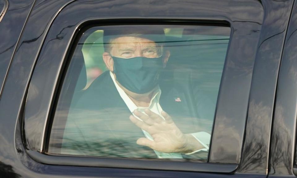 Donald Trump waves from the back of a car outside Walter Reed medical center in Bethesda, Maryland, on 4 October.