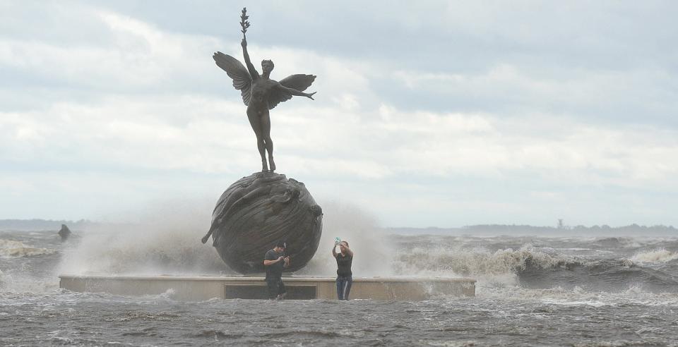 During Hurricane Irma on Sept. 11, 2017, Lee Parker and Laura Brewer take selfies at the "Life" statue in Memorial Park as waves from the St. Johns River break over the bulkhead and railing in Jacksonville.