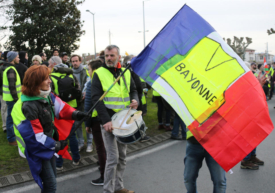 A yellow vest protester holds a french flag with the drawing of a yellow vest as she demonstrates in Saint Jean De Luz, France, Saturday, Jan. 19, 2019. Yellow vest protesters are planning rallies in several French cities despite a national debate launched this week by President Emmanuel Macron aimed at assuaging their anger.(AP Photo/Bob Edme)