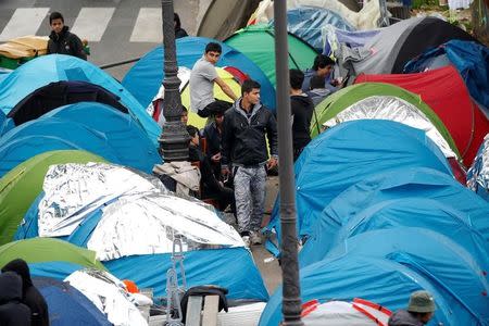 Migrants stand near their tents at a makeshift migrant camp on a street near the metro stations of Jaures and Stalingrad in Paris, France, October 28, 2016. REUTERS/Charles Platiau