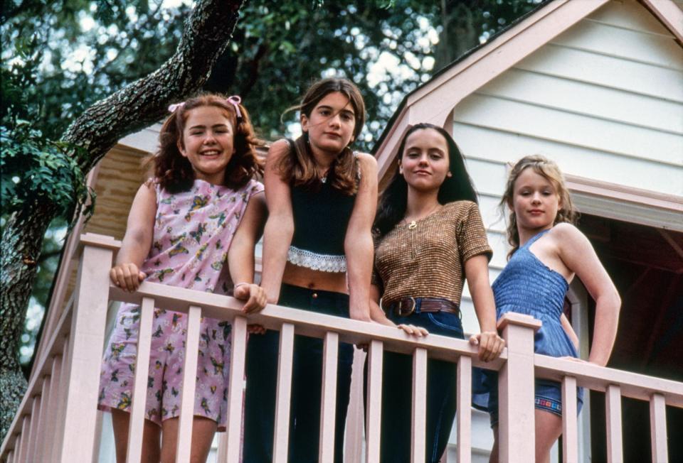 Four little girls standing on a house patio and looking down