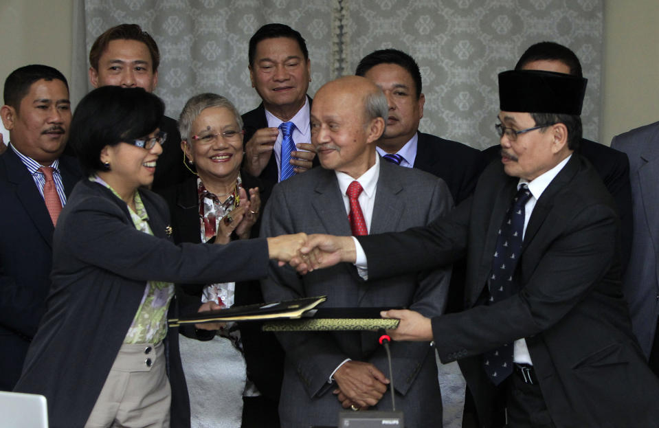 Miriam Coronel-Ferrer, front left, chairperson of Philippine Government Peace Panel, and Mohagher Iqbal, front right, chief negotiator for the Moro National Liberation Front (MNLF), exchange signed documents as Malaysian facilitator Abdul Ghafar Tengku Mohamed, front center, witnesses after the 43rd GPH-MILF Exploratory Talks in Kuala Lumpur, Malaysia, Saturday, Jan. 25, 2014. The Philippine government and the country's largest Muslim rebel group completed talks Saturday on a deal to end four decades of fighting that has killed tens of thousands of people and helped foster Islamic extremism in Southeast Asia. (AP Photo/Lai Seng Sin)