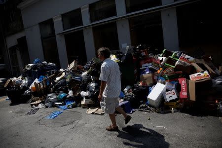 A man walks past a pile of garbage in Piraeus, near Athens, Greece June 26, 2017. REUTERS/Alkis Konstantinidis