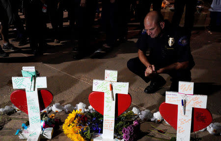 Lt. Jad Lanigan of the Aurora police department looks over crosses for those killed in the Aurora theater shooting, at a vigil on the 5-year anniversary of the tragedy in Aurora, Colorado July 20, 2017. REUTERS/Rick Wilking